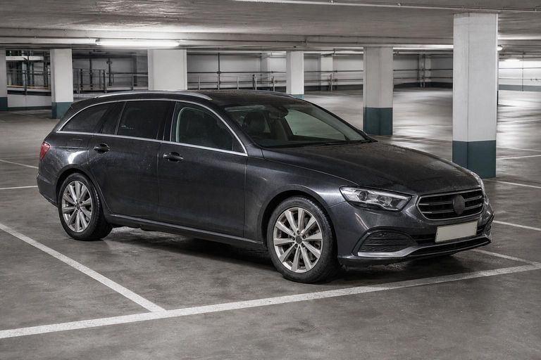 A dark grey estate car parked in an underground car park.