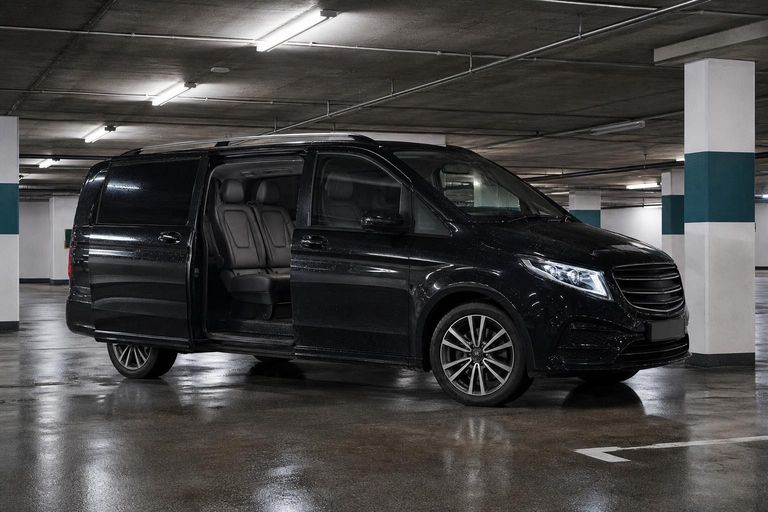 A black seven-seat people-carrier with its sliding door open, parked in an underground car park.